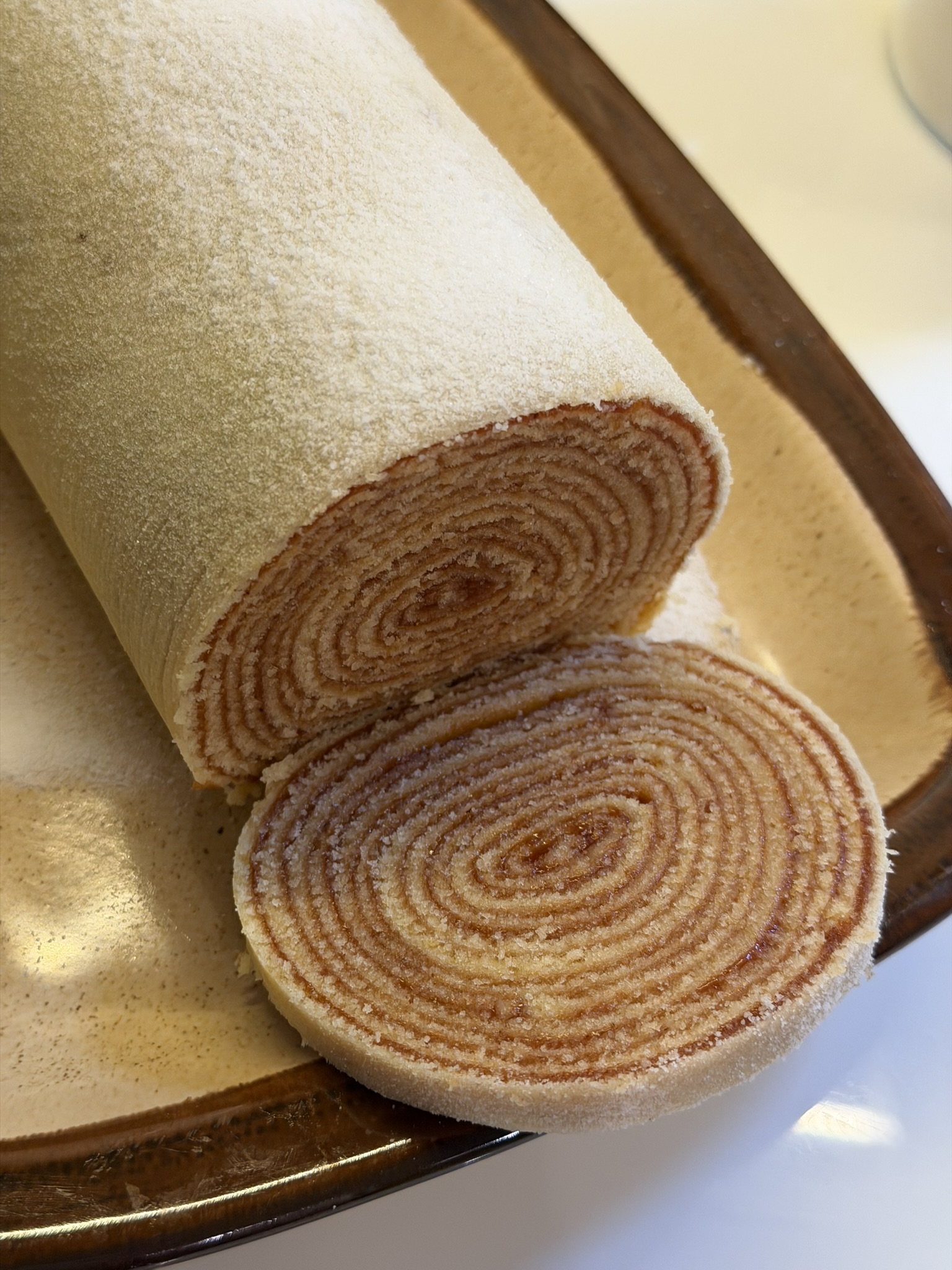 Bolo de rolo de goiabada sendo fatiado, mostrando o espiral de massa e recheio