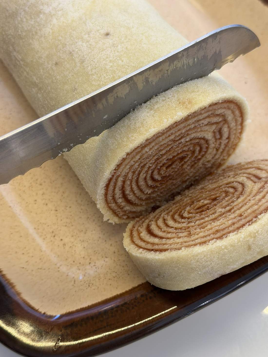Bolo de rolo de goiabada sendo fatiado, mostrando o espiral de massa e recheio